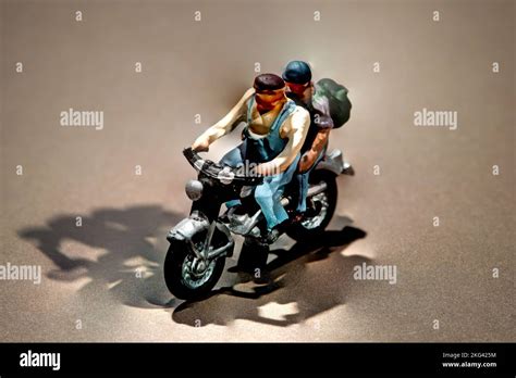 Miniature Men Wearing Backpacks Going For A Trip On A Motorcycle Over A