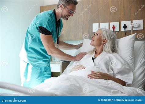 Surgeon Visiting And Talking With Mature Female Patient In Hospital Bed