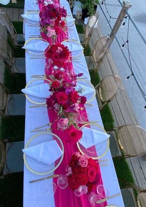 A Long Table Is Set With Pink And Red Flowers