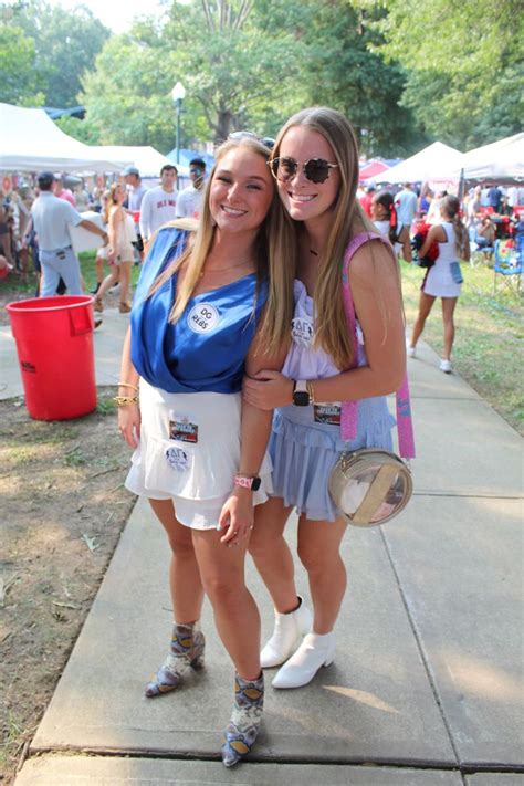 Two Young Women Standing Next To Each Other On A Sidewalk At An Outdoor