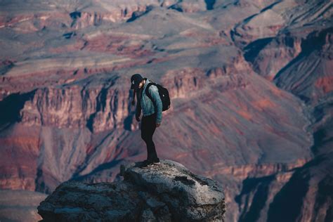 People Man Standing On Rock Cliff Overlooking Canyon During Daytime