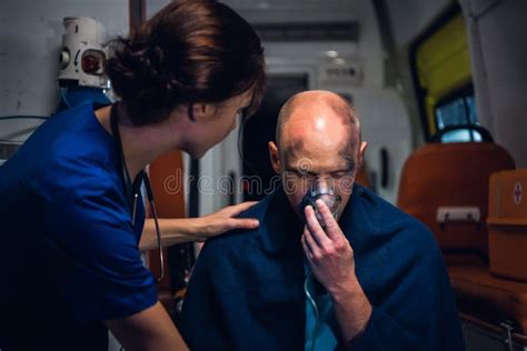 Nurse Puts Her Hand On Man Who Sits In Oxygen Mask In Blanket In The