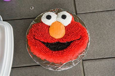 a sesame street cake is decorated with red icing and an orange beaky face