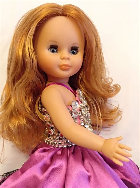 A Doll With Blonde Hair Wearing A Purple Dress