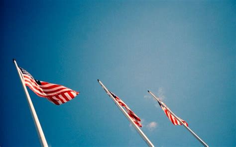 Premium Photo Low Angle View Of American Flags Flying Against Blue Sky