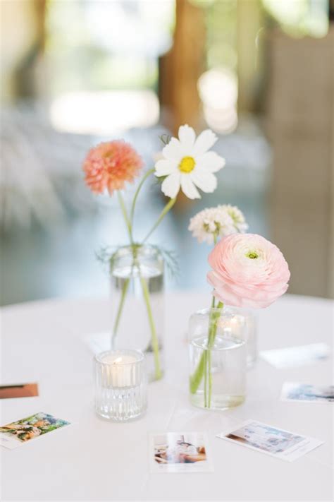 Two Vases Filled With Flowers Sitting On Top Of A White Table Covered