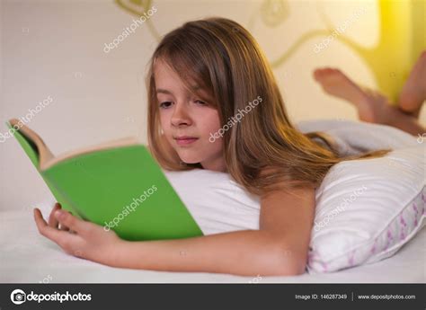 Jeune fille couchée sur le ventre au lit lecture d un livre peu