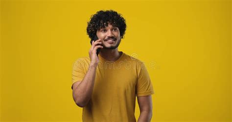 Young Smiling Indian Man Talking On The Phone Answering Phone Call Standing Isolated Over Blue