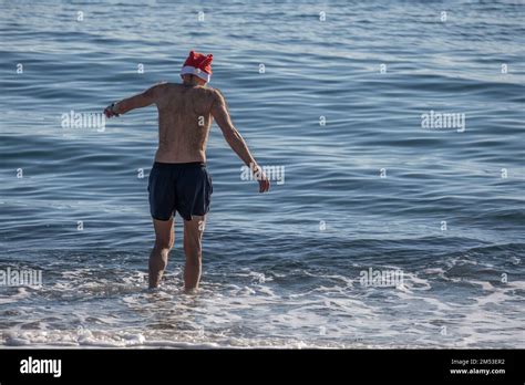 Un hombre que lleva un sombrero de Papá Noel entra en el agua en la