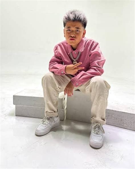 A Young Boy Sitting On Top Of A Cement Bench In Front Of A White Wall