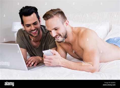 Gay Couple Using Smartphone And Laptop Stock Photo Alamy