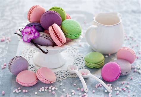 Colorful Macaroons Are In A White Bowl On A Table With Pink And Purple