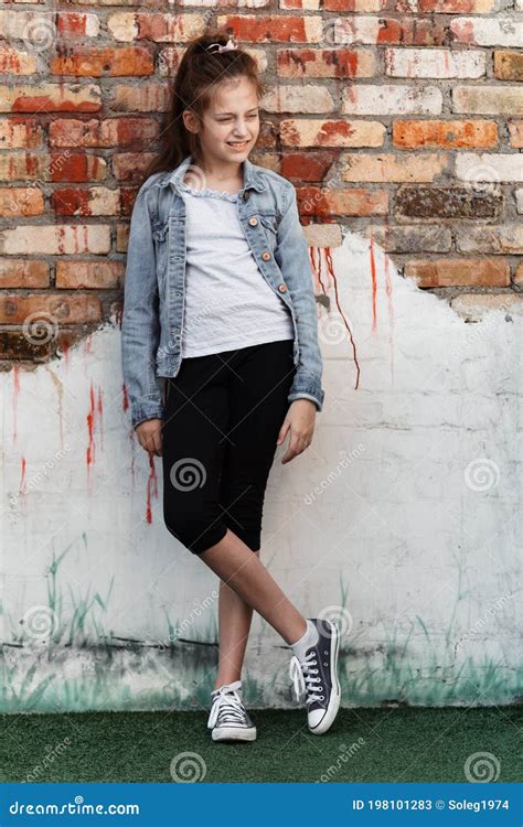 Portrait Of A Beautiful Teenage Girl Posing Against A Brick Wall Stock