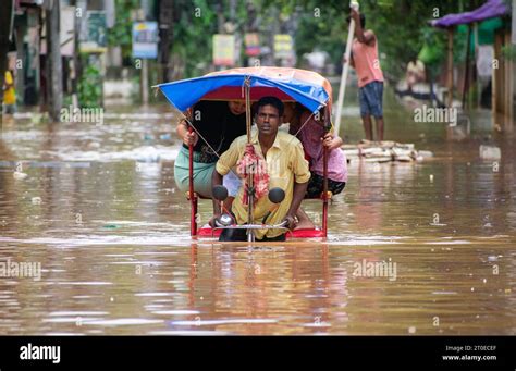 Commuters On A Rickshaw To Cross A Waterlogged Road After Heavy