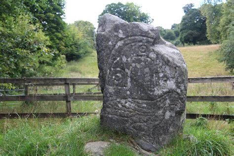 A Large Rock Sitting In The Middle Of A Lush Green Field Next To A