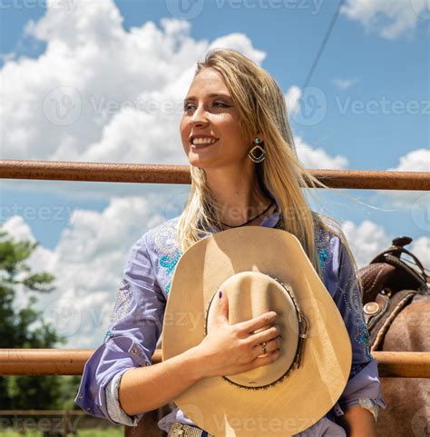 Beautiful Blonde Cowgirl With Hat Standing Near The Horse Ranch