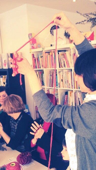 A Group Of People Sitting Around A Table With Yarn On It And Scissors