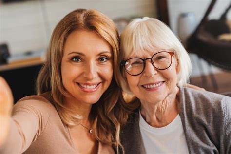 Femme âgée Assise Avec Sa Fille Sur Un Canapé Et Prenant Un Selfie Avec