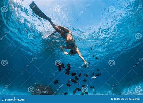 Freediver Girl In Bikini With Fins Glides Underwater In Blue Transparent Ocean Stock Image