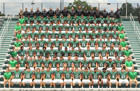 The Football Team Is Posing For A Photo On The Bleachers In Their Uniforms