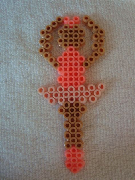 An Orange And Brown Beaded Figure Is On A White Surface With Circles Around It