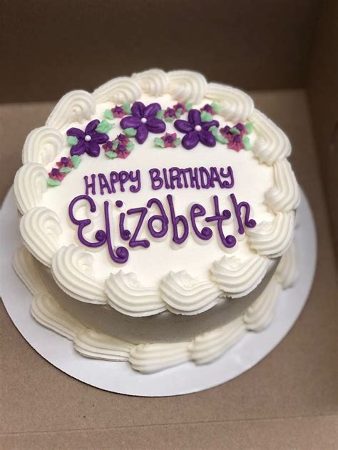 A Birthday Cake With White Frosting And Purple Flowers On The Top That