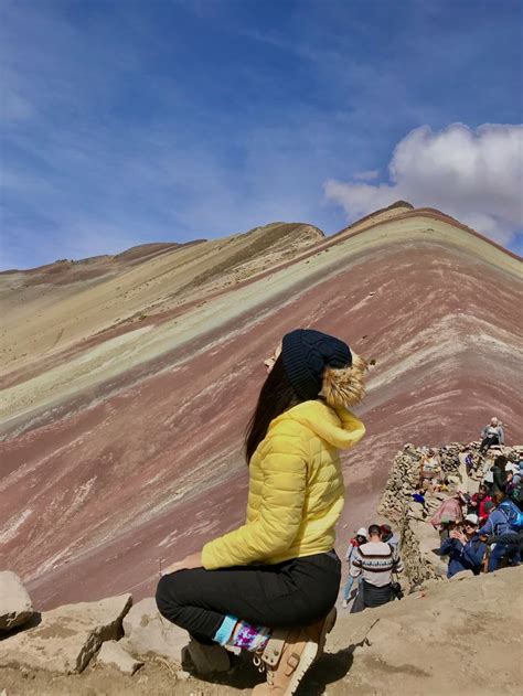 A Woman Sitting On Top Of A Mountain Next To A Group Of People