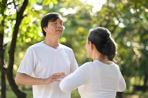 Premium Photo | Calm senior couple doing qi gong or tai chi exercise in ...