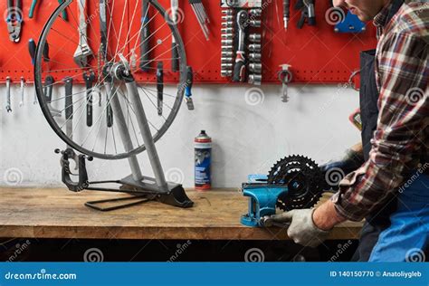 Male Mechanic Working In Bicycle Repair Shop Using Tools Stock Photo