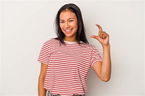 Mujer latina joven aislada sobre fondo blanco sosteniendo algo poco con los dedos índices