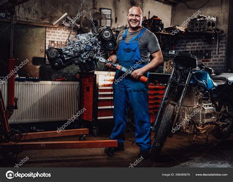 Professional Mechanic Stands Next To The Suspended Flat Engine And