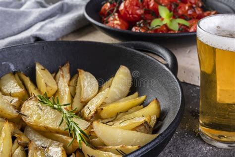 Patatas Asadas Con Romero En Cazuela De Hierro Y Plato De Tomates