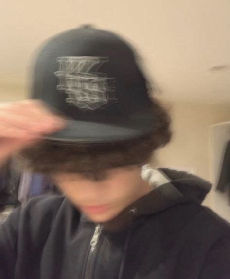 A Blurry Photo Of A Boy Wearing A Black Baseball Cap With The Letter H