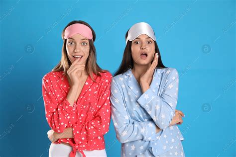 Beautiful Women Wearing Sleeping Masks On Light Blue Background