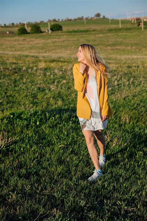 Blonde Woman Walking Through A Green Field At Sunset Stock Image