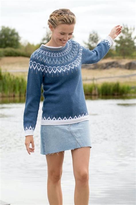 A Woman In A Blue Sweater And Skirt Standing On A Dock Next To The Water