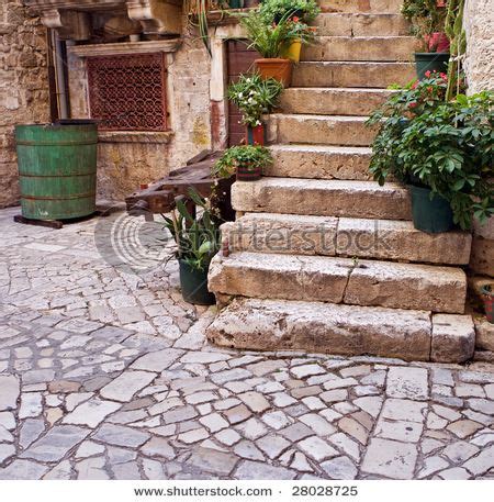 An Alleyway With Stone Steps And Potted Plants