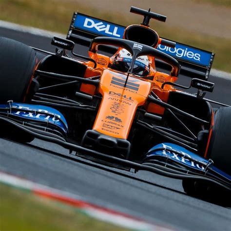 An Orange And Blue Racing Car Driving On A Race Track