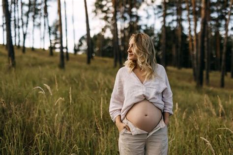 Premium Photo Pregnant Woman With Blonde Hair Standing In A Field Holding Hands On Belly On A