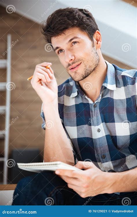 Pensive Young Man Writing In Notepad And Thinking At Home Stock Image