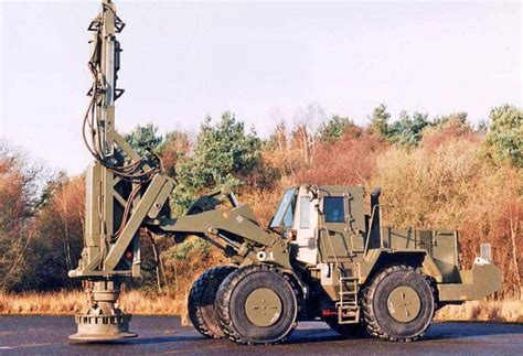 an army vehicle is parked next to a drilling rig