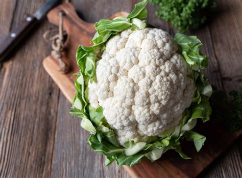 Raw And Uncooked Whole Cauliflower With Green Leaves Isolated On Wooden