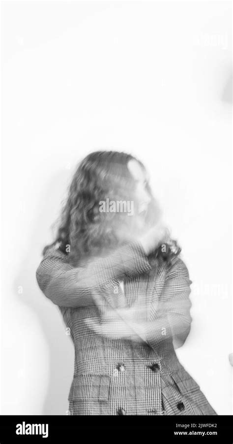 An artistic grayscale of a curly female wearing a suit in motion blur ...