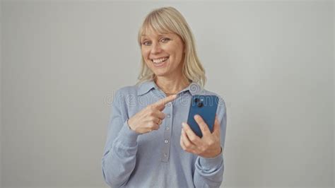 Cheerful Blonde Woman Joyfully Pointing And Smiling Confidently Texting On Her Smartphone On