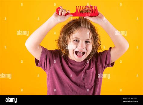 Funny child with curly blonde hair holding comb hairbrush for combing ...