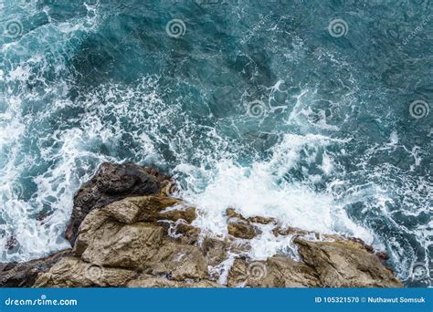 Aerial View Of Ocean Wave Crashing On Rocky Cliff With White Spray And