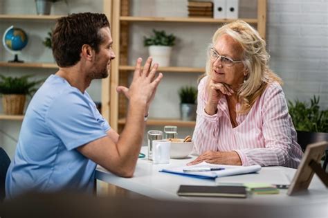 Mulher sênior feliz e seu médico se comunicando após o exame médico