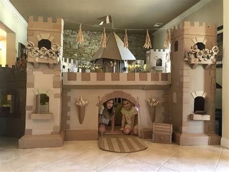 two girls are playing in a cardboard castle