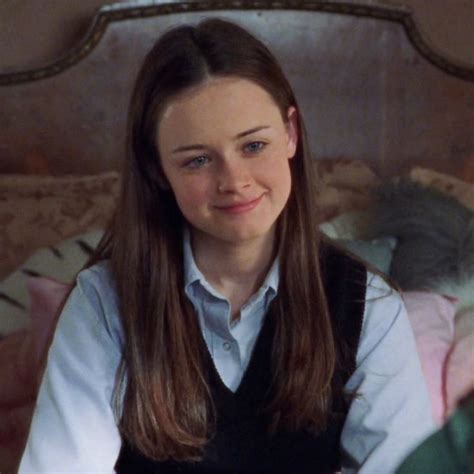 A Woman Sitting On Top Of A Bed Next To A Wooden Headboard And Wearing