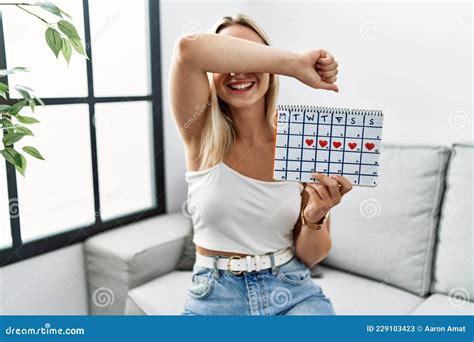 Jeune Femme Blonde Tenant Le Calendrier Cardiaque Souriant Joyeux En Jouant à Peek a Boo Avec